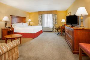 a hotel room with a bed and a flat screen tv at Holiday Inn Express & Suites Bloomington, an IHG Hotel in Bloomington
