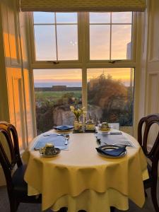 a table with a yellow table cloth and a window at Tides Reach Guest House in The Mumbles