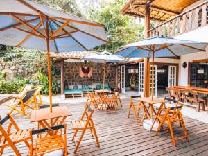 um grupo de mesas e cadeiras com guarda-sóis num deque em VELINN Hotel Santa Tereza em Ilhabela