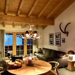 貝特默阿爾卑的住宿－Chalet Sirius Dachwohnung，客厅配有桌子和吊灯