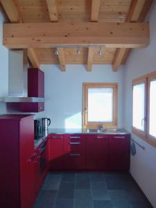 - une cuisine avec des placards rouges et un évier dans l'établissement Chalet Sirius Dachwohnung, à Bettmeralp