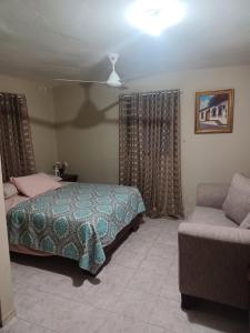 1 dormitorio con 1 cama y 1 sofá en Alexandra Guridy Room For Rent, en Los Tres Ojos de Agua
