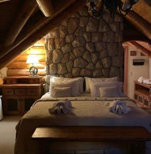 - une chambre avec un grand lit dans un mur en pierre dans l'établissement Las Baitas, à San Carlos de Bariloche