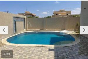 a large swimming pool in a backyard with a fence at فيلا محمد بدر in Naj‘ al Aḩwāl