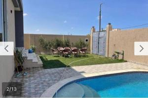 a backyard with a table and chairs and a pool at فيلا محمد بدر in Naj‘ al Aḩwāl