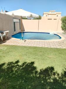 a swimming pool with an umbrella in a yard at فيلا محمد بدر in Naj‘ al Aḩwāl