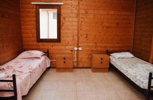 Habitación de madera con 2 camas y ventana en Village of Peace - House 25, en Shkodër
