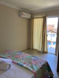 a bedroom with a bed and a window with a window at POUSADA RECANTO DULE in Guarapari