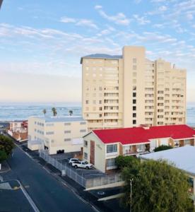 a building with a red roof next to the ocean at Nautica Strand in Cape Town