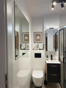 a white bathroom with a toilet and a sink at Apartament Powiśle in Warsaw