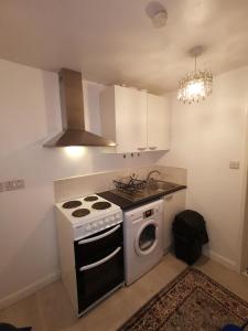 a kitchen with a stove and a washing machine at Argyll Studio Apartment - Luton Airport in Luton