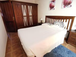 a bedroom with a white bed with a wooden headboard at Alma y Sol in La Caleta