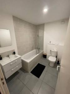 a bathroom with a tub and a toilet and a sink at Ô Calme ! Logement Rénové à Neuf - Une Expérience Unique - Wifi Gratuit in Grenoble