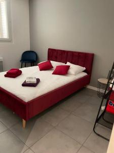 a large bed with red pillows at Ô Calme ! Logement Rénové à Neuf - Une Expérience Unique - Wifi Gratuit in Grenoble