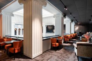 a restaurant with orange chairs and tables and columns at Radisson Blu Plaza Hotel, Helsinki in Helsinki