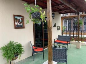 un patio con 2 sillas, una mesa y una maceta en El Mesón de los Abuelitos, en Retalhuleu