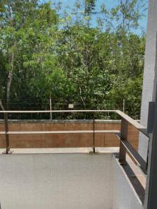 d'un balcon avec un banc et des arbres en arrière-plan. dans l'établissement Amplio departamento con alberca, à Playa del Carmen