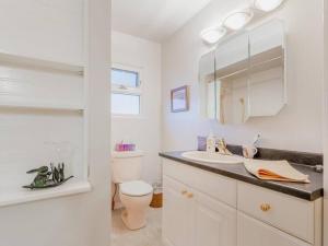 a white bathroom with a toilet and a sink at Cozy Capitol Hill Bungalow - 3BD/2BA Retreat in Burnaby