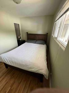 een slaapkamer met een bed met witte lakens en een raam bij Cozy Capitol Hill Bungalow - 3BD/2BA Retreat in Burnaby