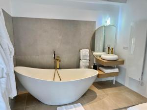 una grande vasca bianca in un bagno con specchio di Domaine de Mende Brenoux Suites & SPA a Mende