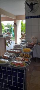 una línea de buffet con muchos platos de comida en Pousada Tartaruga en Cumbuco