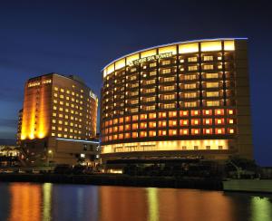 a lit up hotel building next to a body of water at Loisir Spa Tower Naha in Naha
