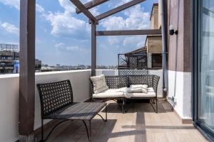 a balcony with two chairs and a couch on a roof at CityHeart Studio in Bucharest