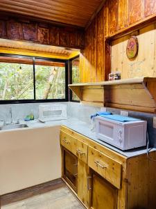 a kitchen with wooden cabinets and a microwave on a counter at Cabañas La Montaña Mountain Lodge in Monteverde Costa Rica