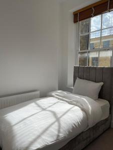 a bedroom with a white bed with a window at Kensington Luxury Apartments in London