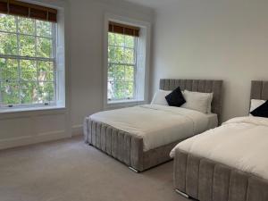 a bedroom with two beds and two windows at Kensington Luxury Apartments in London