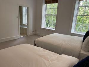 1 dormitorio con 2 camas y 2 ventanas en Kensington Luxury Apartments, en Londres