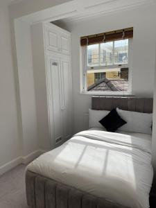 - une chambre avec un grand lit blanc et une fenêtre dans l'établissement Kensington Luxury Apartments, à Londres