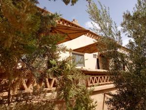 een huis met een balkon en bomen ervoor bij Dar Mezyana Dades in Aït Idaïr