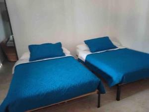 two beds in a room with blue sheets and pillows at Alojamiento Rural - La Perla in Filandia
