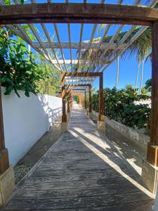 una pasarela de madera con pérgola en la playa en Acceso a la playa 2 hab 3 camas 6 pax bella piscin, en Punta Cana