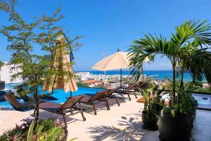 a patio with chairs and an umbrella and a pool at Stayon5a Av penthouse with PrivatePool in Playa del Carmen