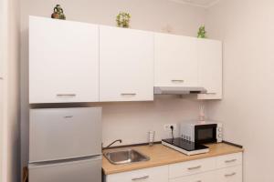 a kitchen with white cabinets and a sink and a microwave at B&B Civicocento in Torre del Greco