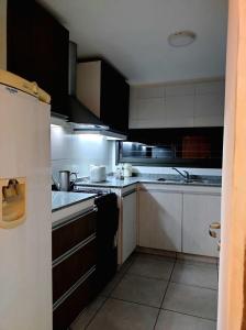 una cocina con armarios negros y electrodomésticos blancos en Montaña Sol Malbec, en Ciudad Lujan de Cuyo