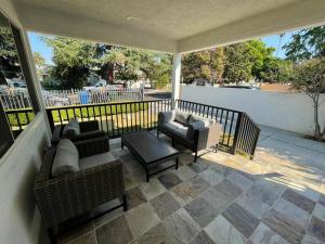 un porche con 2 sofás, mesa y sillas en Charming Bright Traditional Home in Sherman Oaks en Sherman Oaks