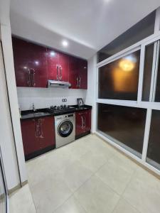 cocina con armarios rojos y lavadora en Appartement Idéal : Proximité, Confort et Élégance en Tetuán