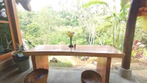 una mesa de madera con 2 sillas frente a una ventana en Bali Jungle Taksu, en Tampaksiring