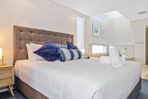 een slaapkamer met een groot wit bed met blauwe kussens bij Beachside Bliss 1 Bedroom Park View Villa in Mandurah