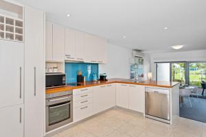 eine Küche mit weißen Schränken und einer Arbeitsplatte in der Unterkunft Beachside Bliss 1 Bedroom Park View Villa in Mandurah