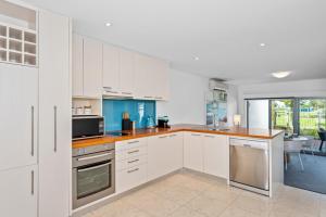 a kitchen with white cabinets and a counter top at Beachside Bliss 1 Bedroom Park View Villa in Mandurah