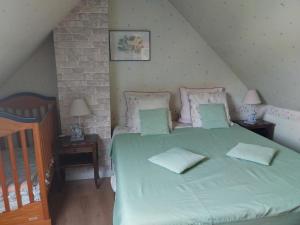 een slaapkamer met een bed met groene lakens en kussens bij Gîte chaleureux avec jardin, poêle à bois et wifi, entre St Omer et Boulogne sur Mer - FR-1-376-80 in Coulomby