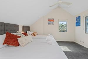 a white bedroom with two beds and a ceiling fan at Beachside Bliss 2 Bedroom Family Villa in Mandurah