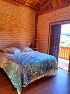 een slaapkamer met een bed en een bakstenen muur bij Chalés Roma in Santo Antônio do Pinhal
