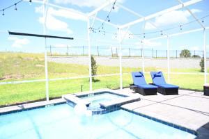 a patio with two blue chairs and a swimming pool at Luxurious 8-Room Oasis near Disney in Kissimmee