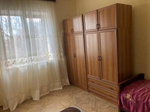 a bedroom with a large wooden cabinet next to a window at Собственный дом в фруктовом саду 