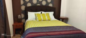1 dormitorio con 1 cama con edredón amarillo y morado en Boutique Amaru Wasi, en Cusco